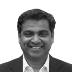 Retrato a preto e branco de Durga Prasad Vemula, de fato e sorridente.