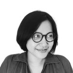 Retrato a preto e branco de Ketut Sulistyawati, de camisa e sorridente.