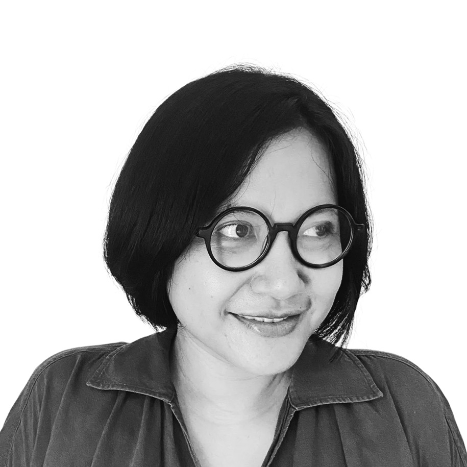 Retrato a preto e branco de Ketut Sulistyawati, de camisa e sorridente.