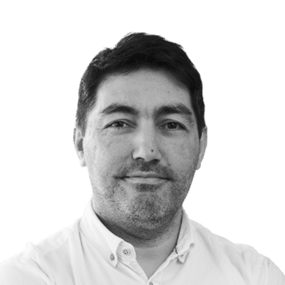 Retrato a preto e branco de Ricardo Luiz, de camisa, sorrindo levemente.