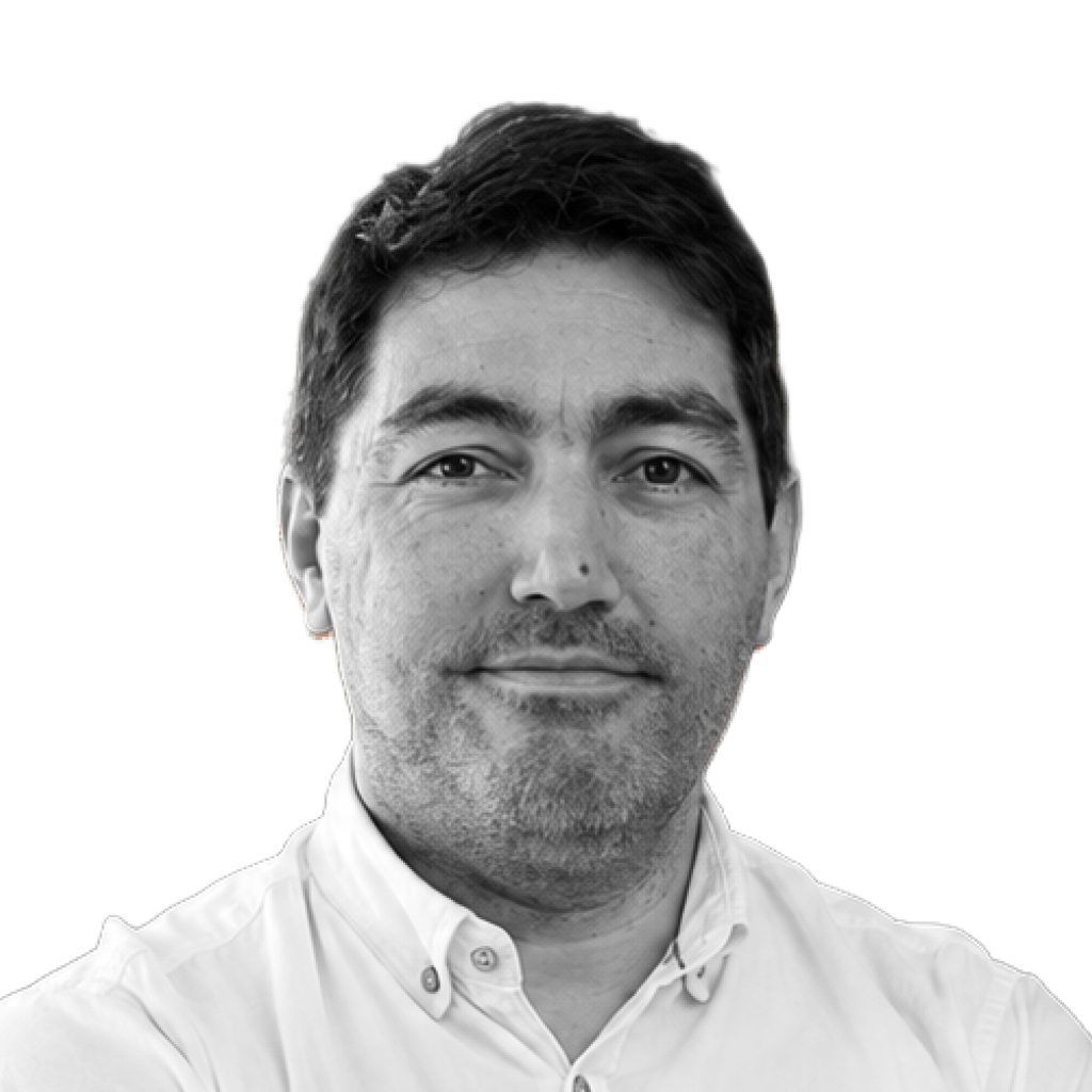 Retrato a preto e branco de Ricardo Luiz, de camisa, sorrindo levemente.