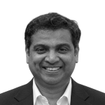 Retrato a preto e branco de Durga Prasad Vemula, de fato e sorridente.