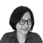 Retrato a preto e branco de Ketut Sulistyawati, de camisa e sorridente.