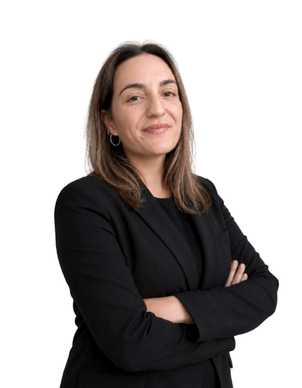 Retrato Marta Monterde, de cabelo castanho claro, sorridente, posando de perfil com os braços cruzados. Veste um blazer preto sobre uma camisola preta. O fundo da imagem é totalmente branco e isolado.
